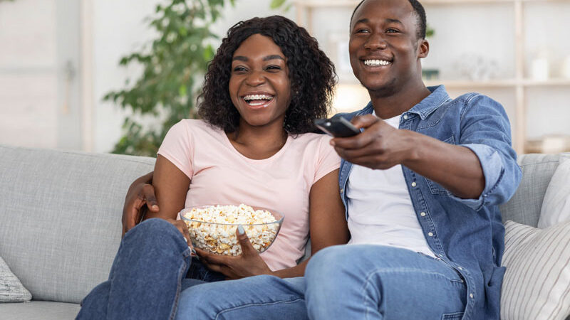 Happy black family watching movie together at home